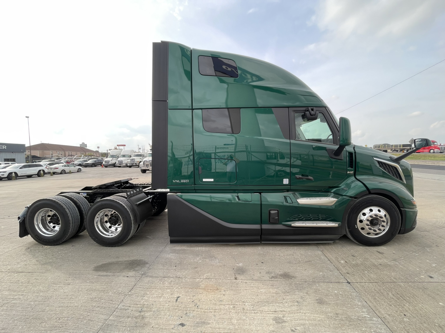 Side view of a green Volvo VNL64T860 tractor, cab with sleeper, showing rear wheels and fuel/air tanks.