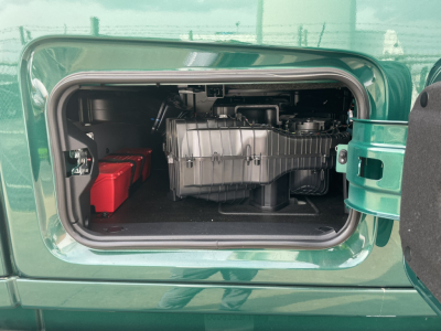 Volvo VNL64T860 truck engine bay showing front compartment with a silver engine component and a red battery pack visible in storage area.