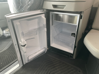 Mini-fridge in a Volvo VNL64T860 cab with door open showing empty freezer and fridge compartments.