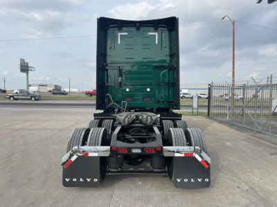 Rear view of a Volvo VNL64T860 tractor with green cab, dual rear axles, and black mud flaps showing VOLVO branding.