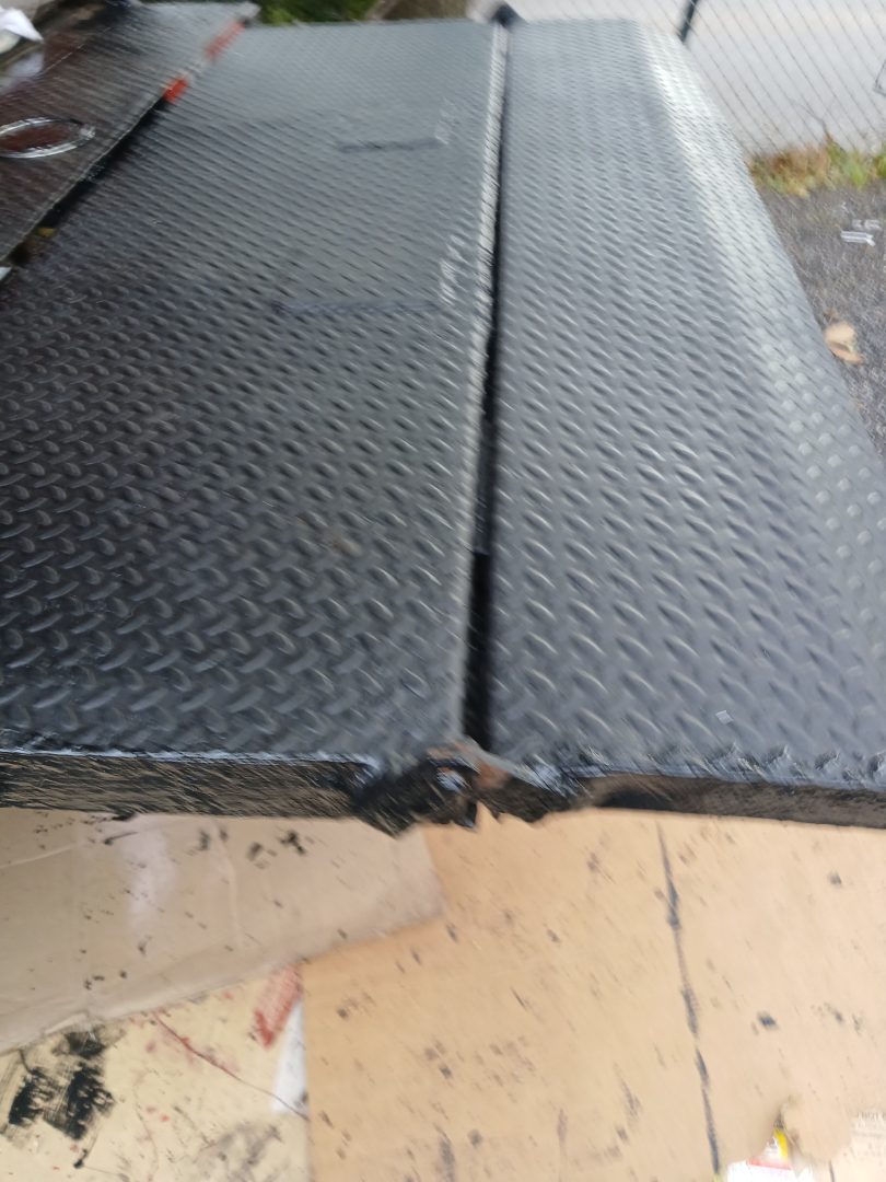 Diamond plate metal truck bed with seam in center and edge damage visible on the 2004 Mitsubishi FH truck bed area.