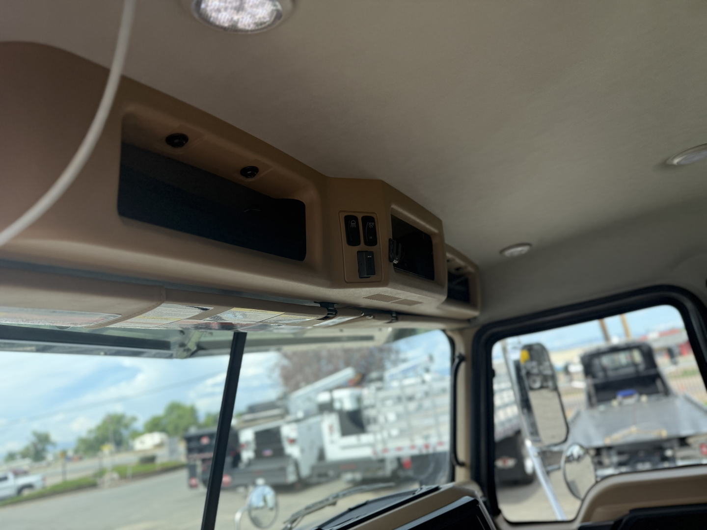 Cab interior of a Mack GR64F showing overhead console with controls, vents, and storage panel.