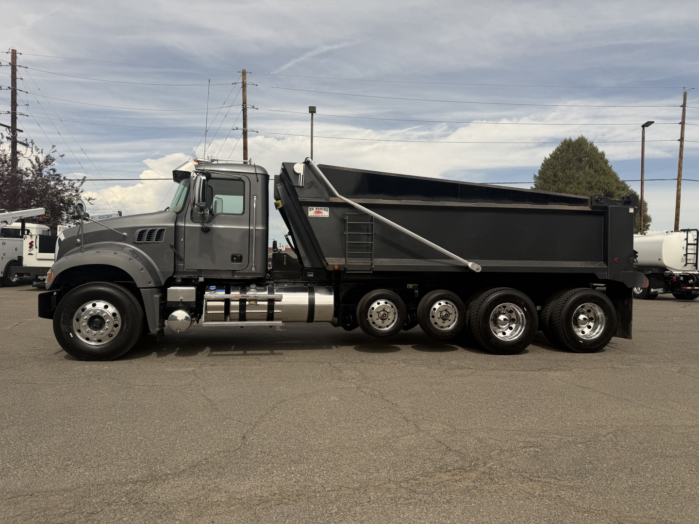 Mack GR64F dump truck side view showing dump bed and multiple axles.