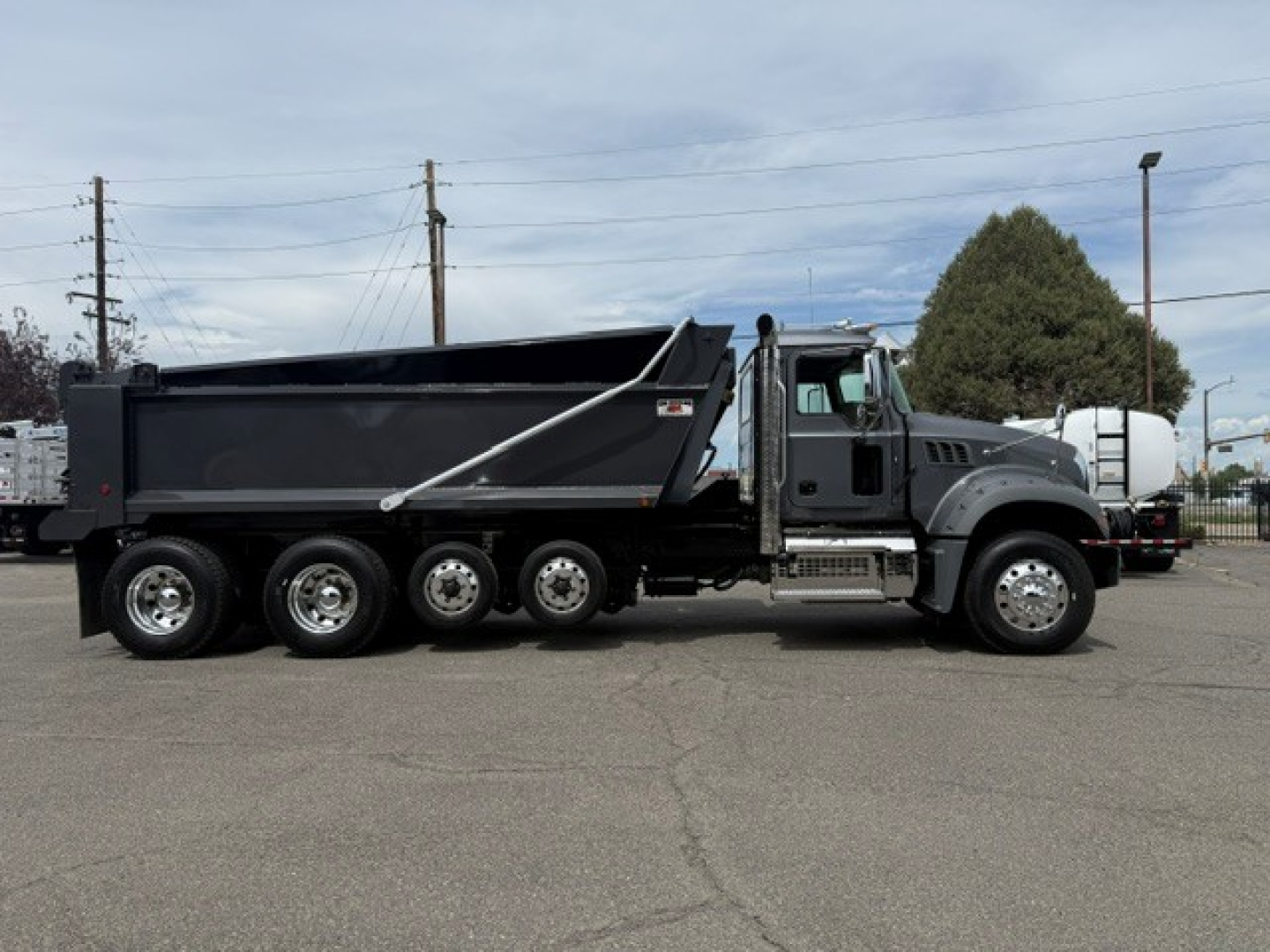 Dump truck side view showing Mack GR64F with multi-axle rear, large dump bed, and front cab with wheels; VIN plate and stock number not legible.