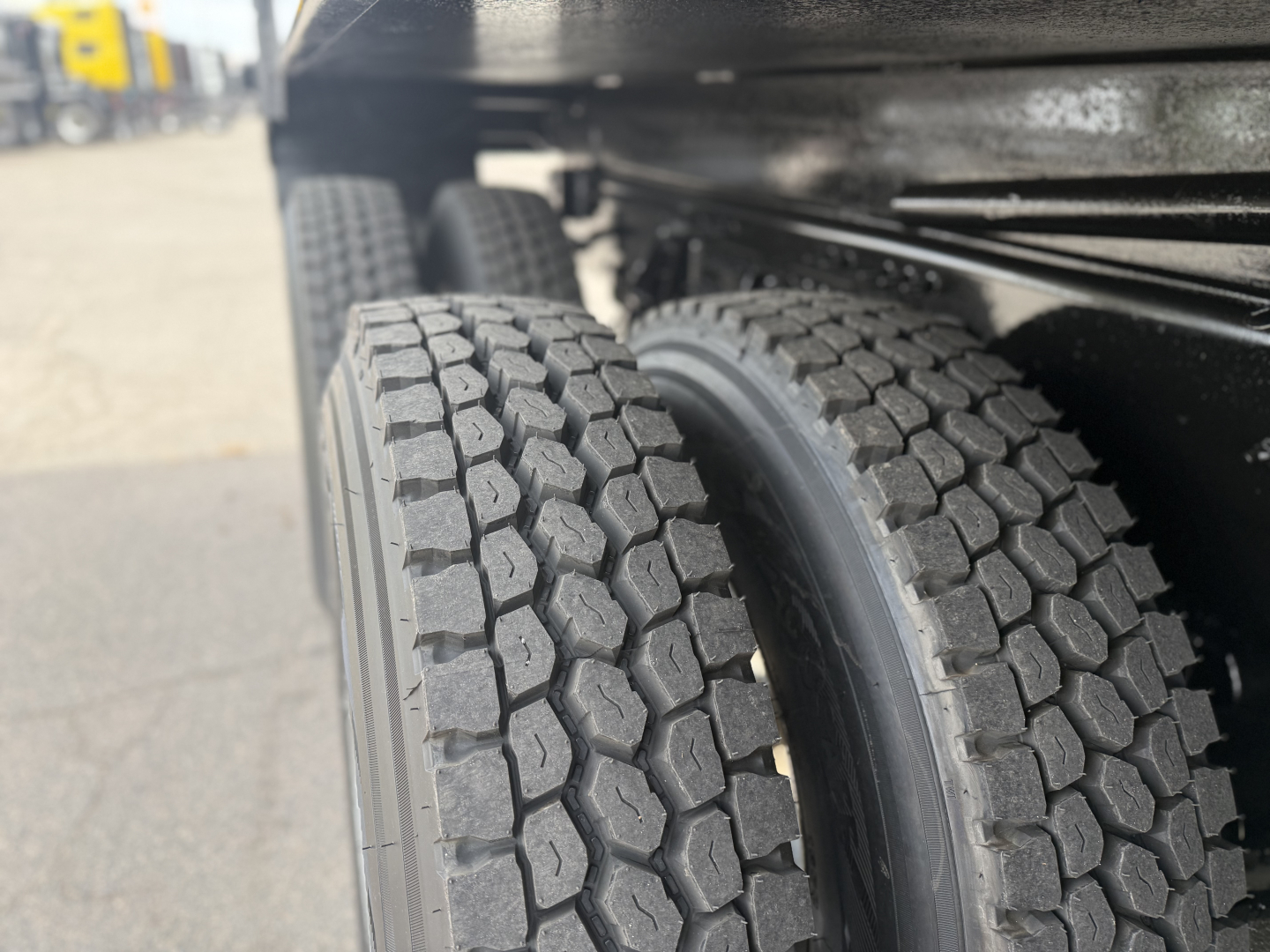 Dual rear truck tires on a Mack GR64F dump truck showing heavy tread pattern and wheel housings.