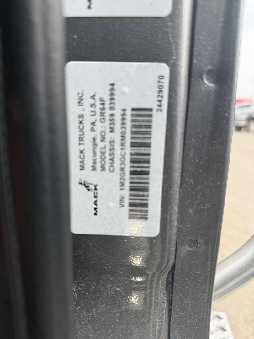 Truck door frame label showing Mack Trucks Inc. Made in USA with VIN and barcode; vertical text on label includes MACK TRUCKS INC. and USA MAKER; nearby numbers and barcodes.