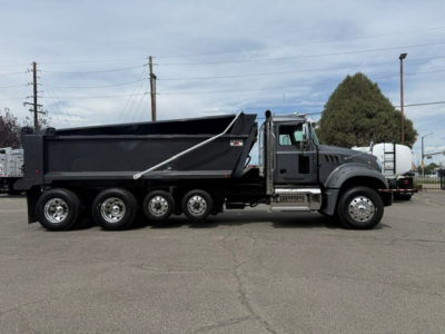 Dump truck side view showing Mack GR64F with multi-axle rear, large dump bed, and front cab with wheels; VIN plate and stock number not legible.