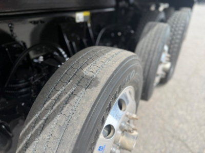 Truck wheel area showing front tire and dual rear axle on a 2024 Mack GR64F dump truck with visible tire treads and rim details.