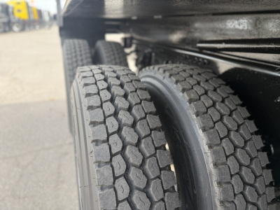Dual rear truck tires on a Mack GR64F dump truck showing heavy tread pattern and wheel housings.