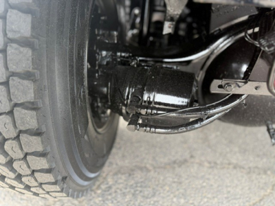 Mack GR64F truck wheel and suspension components in view showing axle and driveshaft joint.