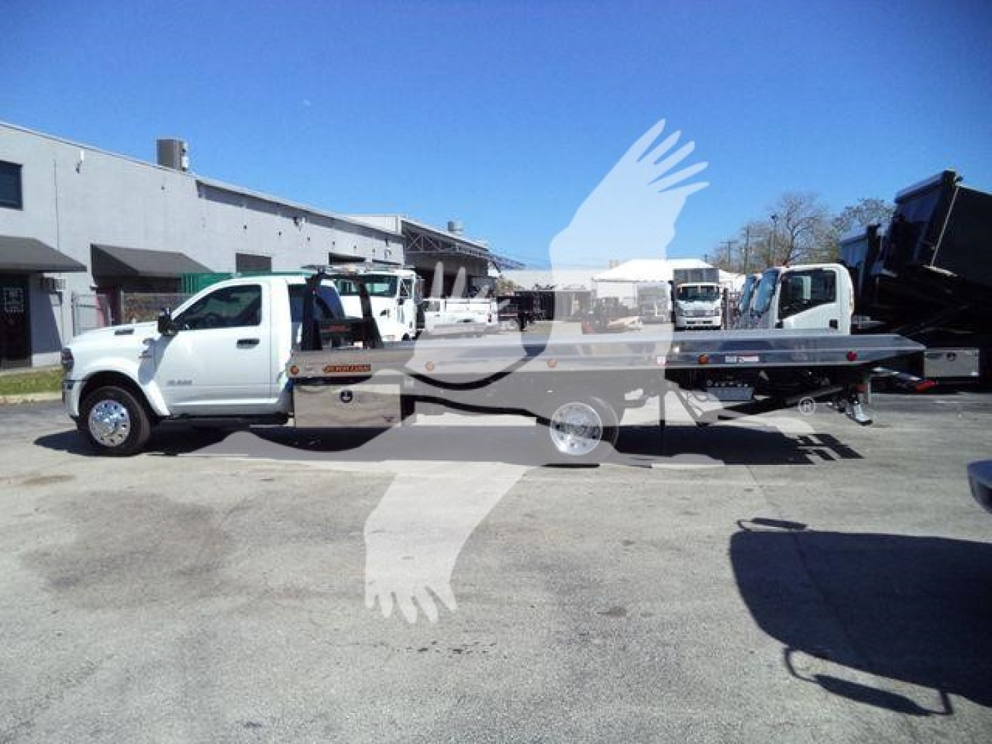 Flatbed tow truck mounted on Ram 5500 chassis with Big Horn trim, side view showing cab and long bed.
