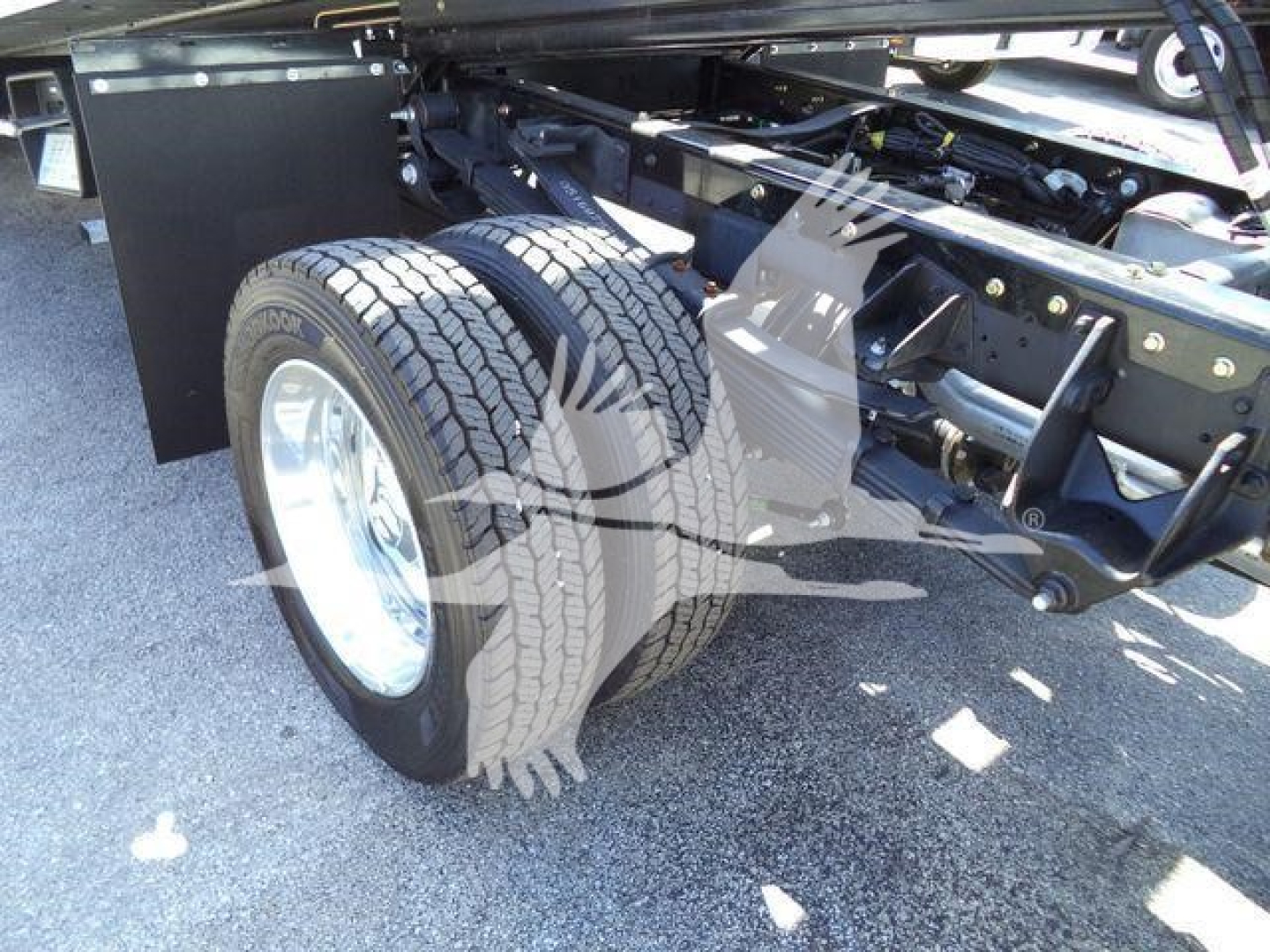 Truck chassis and dual rear wheels showing suspension and frame components under a Ram 5500 rollback bed.