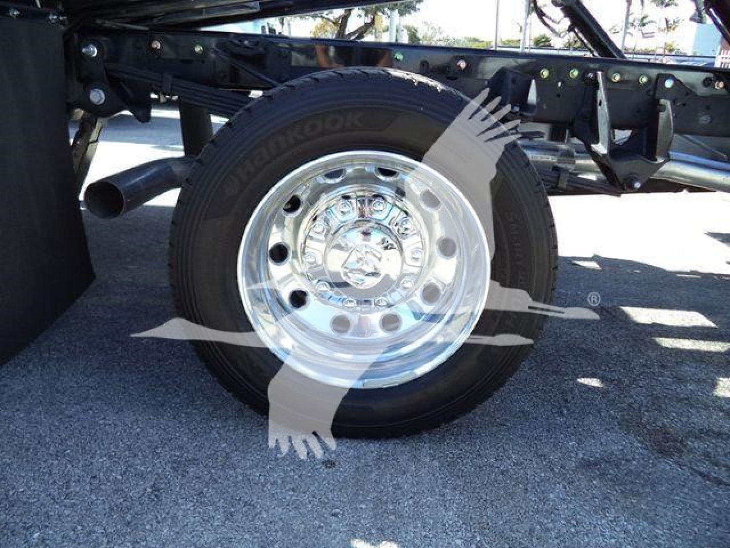 Wheel and tire of a Ram 5500 rollback truck visible with chrome hubcap and Hankook tire. Partial undercarriage with frame and suspension components.