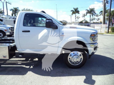 Ram 5500 front half view with rollback bed, white single-cab pickup, large chrome wheel, side mirror, RAM badge, F curb shadow.