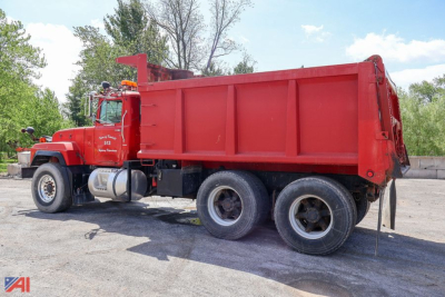 Dump truck side view showing red Mack RD690S with a large open-top cargo bed and dual rear axles.