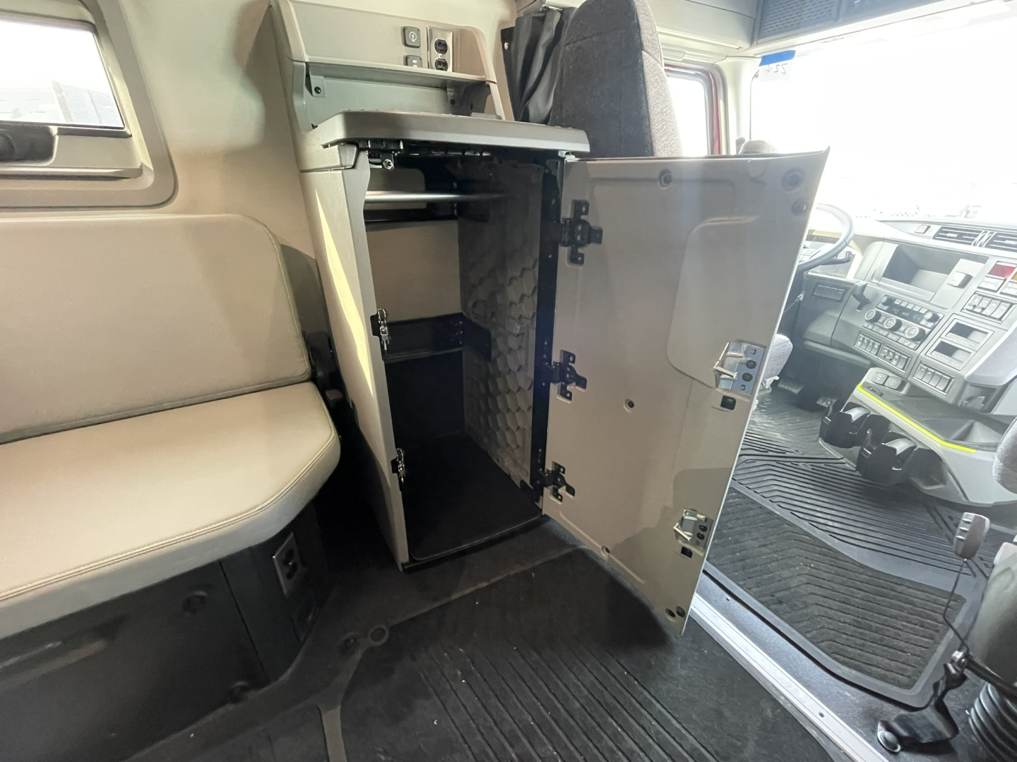 Volvo VNL64T860 cab interior showing open cabinet/storage compartment with shelves near driver seat. Dashboard and steering area visible in background.