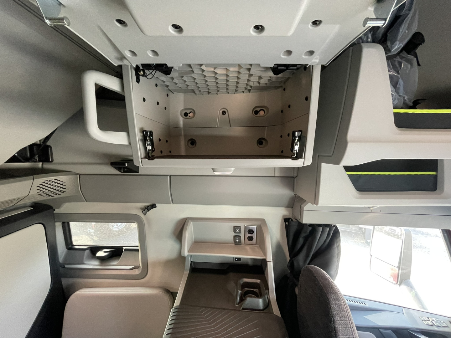 Interior truck cab overhead storage area with metal mounting rails and empty compartments; Volvo VNL64T860 sleeper cab interior view.