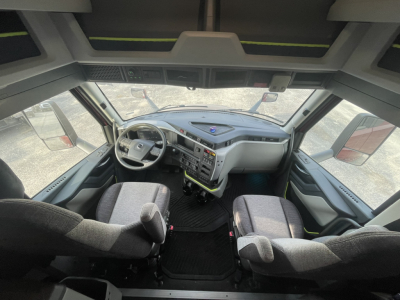 Cab interior of a Volvo VNL64T860 truck showing steering wheel, dashboard, and two front seats from a high vantage point.