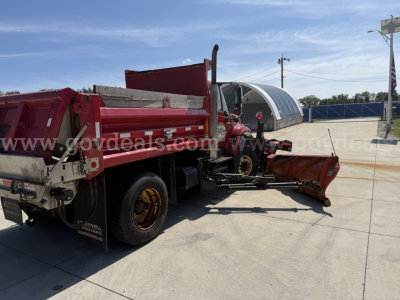 Truck bed and snow plow attachment on a 2012 International 7400 dump truck viewed from side rear