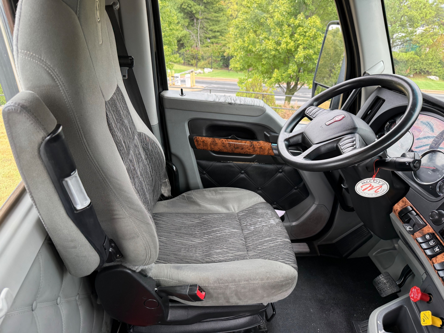 Kenworth T880 truck cab interior showing steering wheel, driver seat, and dashboard with wood trim accents.