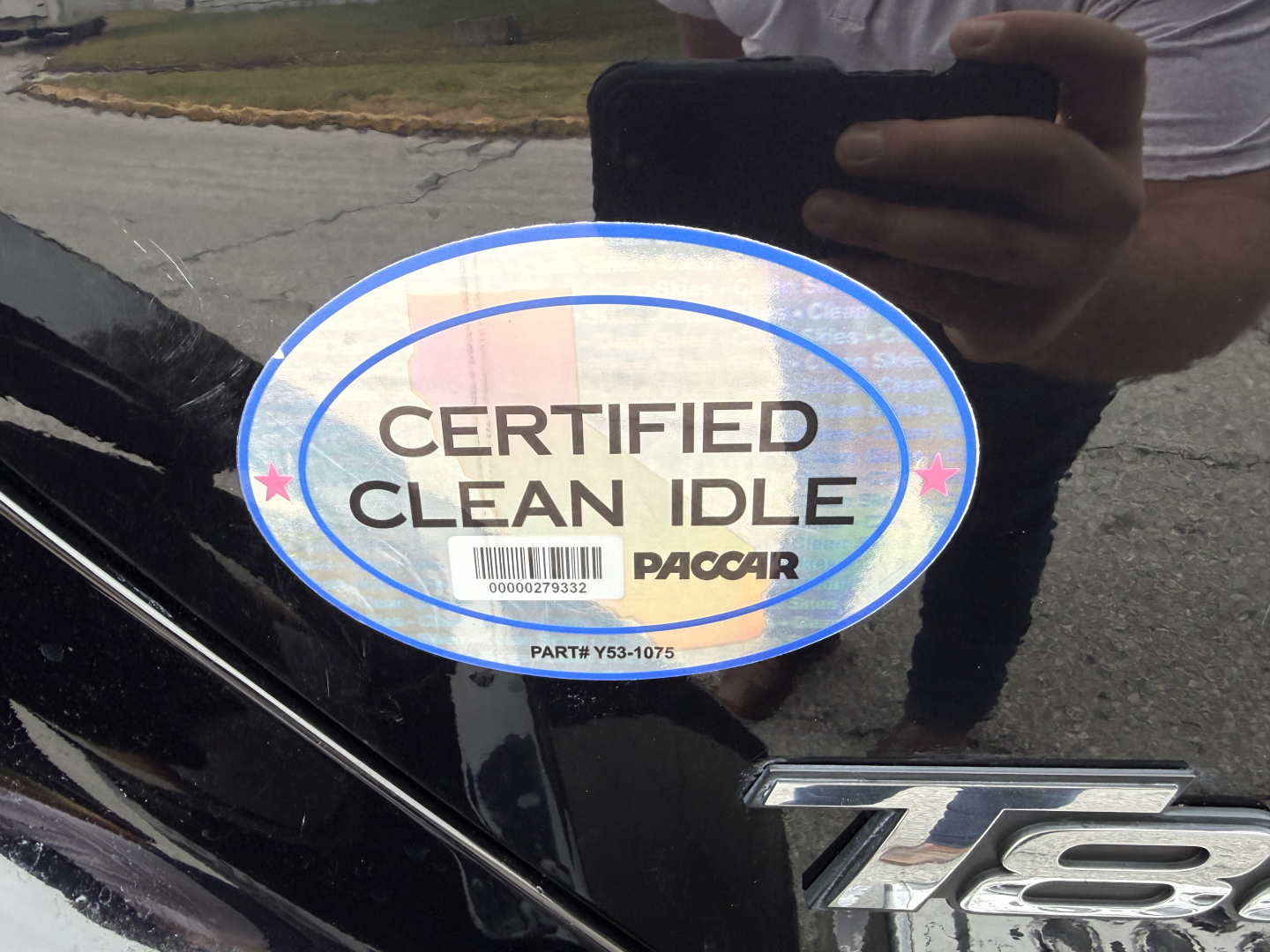 Kenworth T880 emblem with certified clean idle PacCAR stamp and reflection of person taking photo