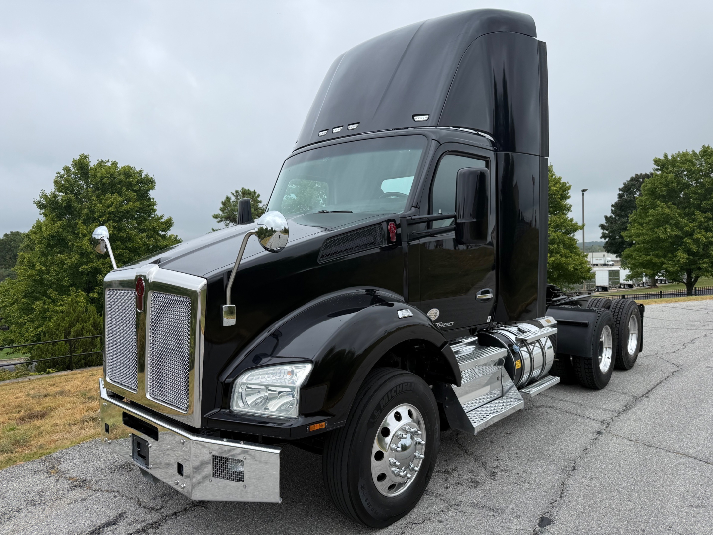 Kenworth T880 conventional daycab tractor in black, front and side view, with chrome grille, dual mirrors, and raised sleeper cab top