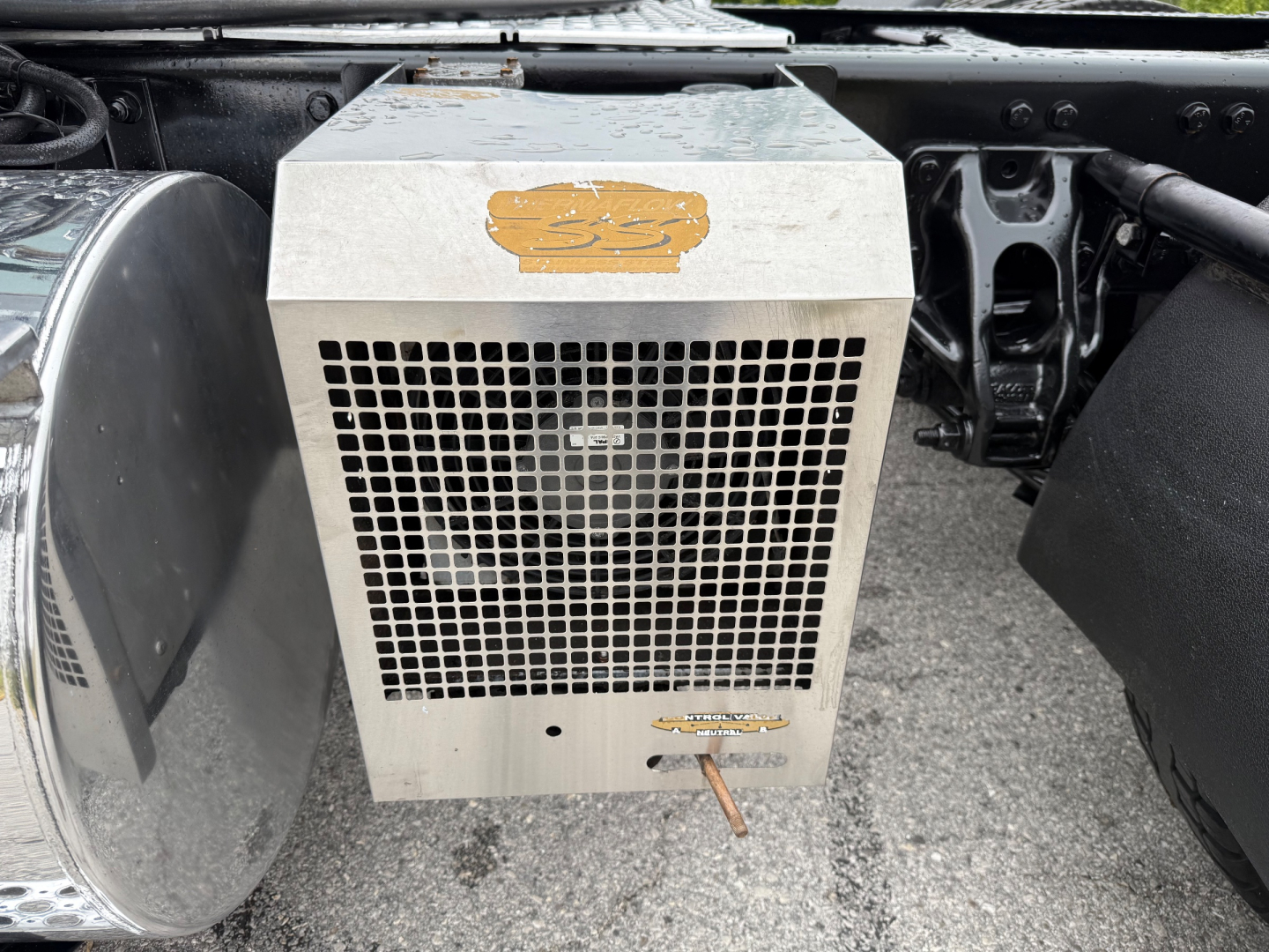 Kenworth T880 under-hood component showing a rectangular metal cooling unit with a mesh grille and a small emblem sticker on top.