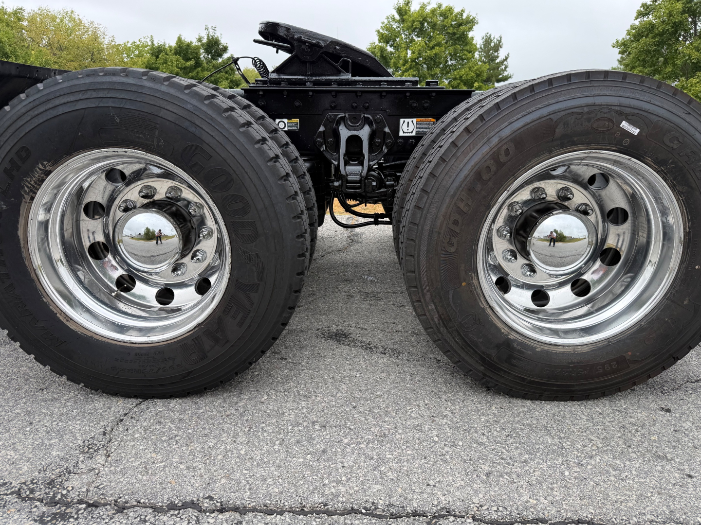 Twin rear wheels of a 2020 Kenworth T880 chassis showing chrome wheels and dual tires with center hubcaps; part of the fifth wheel and drive components visible.