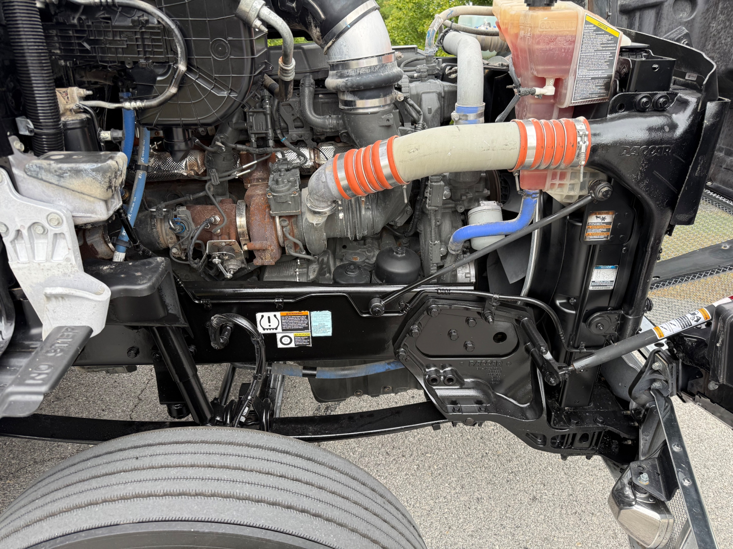 Kenworth T880 engine bay front-left view with hoses, wiring, and radiator area visible.