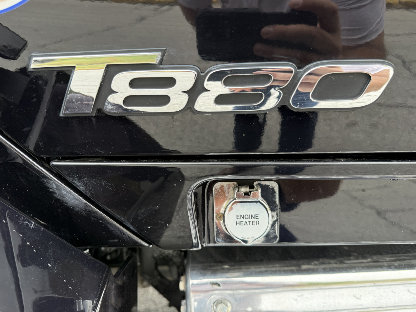 Kenworth T880 emblem with 'ENGINE HEATER' cap visible on black truck fender, 180 badge chrome letters.