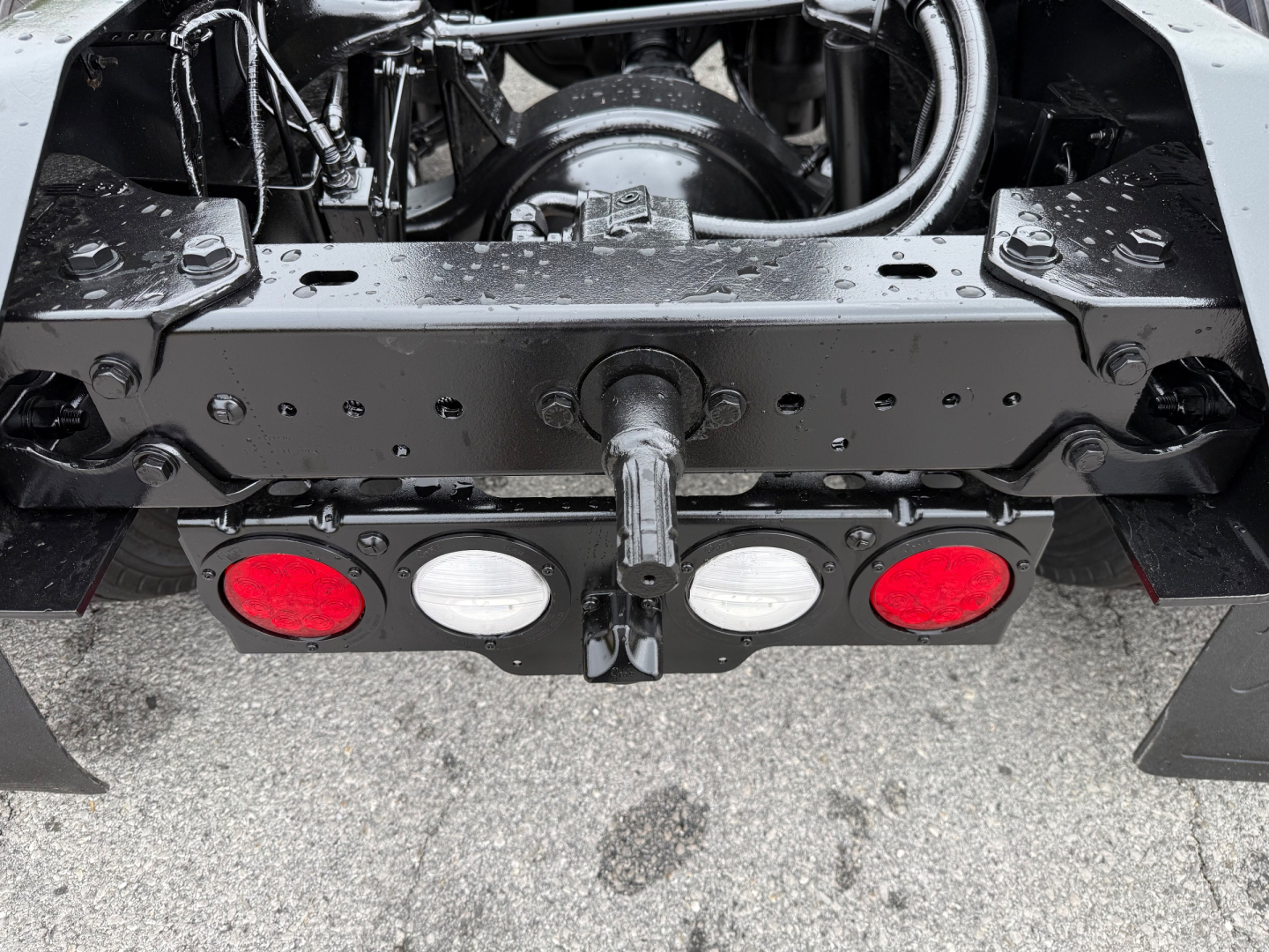 Kenworth T880 rear view showing drivetrain and tow hitch assembly with frame rails, lights, and suspension components.