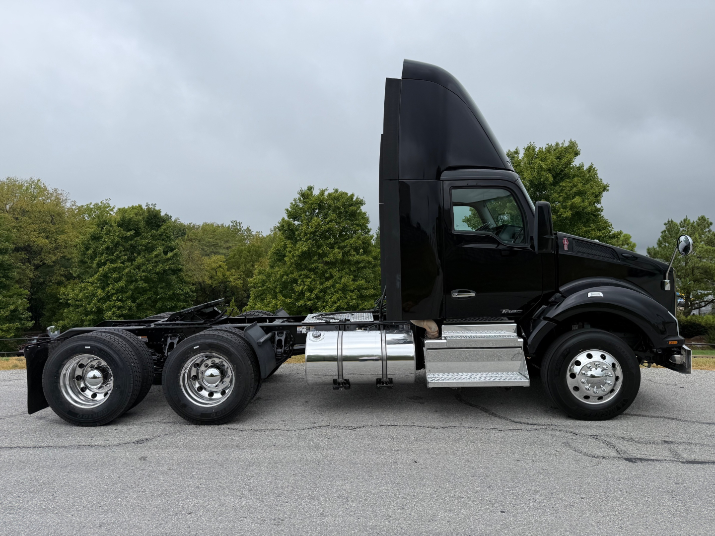 Kenworth T880 tractor-trailer side profile showing cab and chassis with dual rear axles, black paint, chrome fuel tanks and steps.