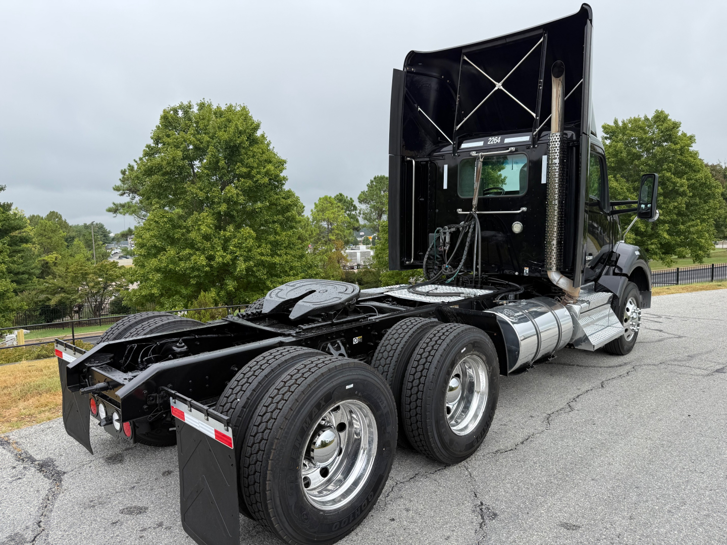 Kenworth T880 truck chassis with raised sleeper cab, dual rear axles, and fifth wheel. View from rear left side showing tires and chassis.
