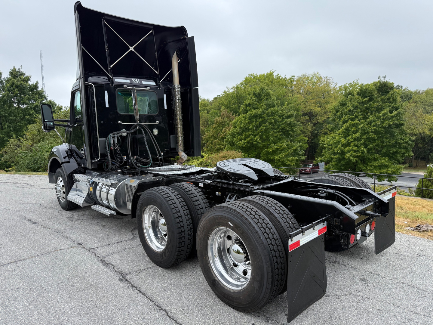 Kenworth T880 truck chassis with dual rear axles and raised cab, side view showing fuel tanks and fifth wheel area.
