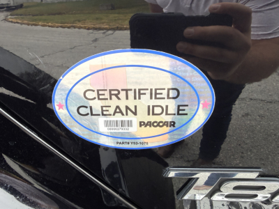 Kenworth T880 emblem with certified clean idle PacCAR stamp and reflection of person taking photo