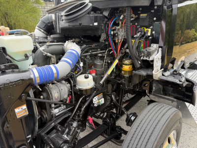 Kenworth T880 engine bay showing coolant reservoir, turbo intake, hoses, wiring, and engine components with blue silicone intake boot.