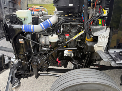 Kenworth T880 engine bay showing coolant reservoir, hoses, belts, and various engine components in operation-ready configuration.