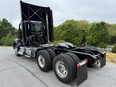 Kenworth T880 truck chassis with dual rear axles and raised cab, side view showing fuel tanks and fifth wheel area.