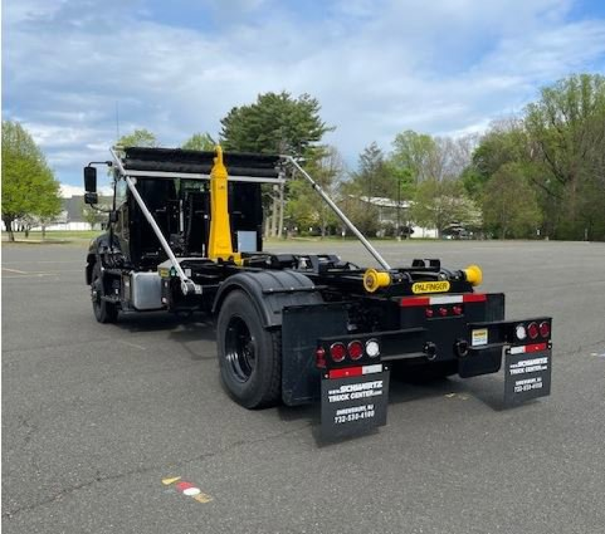 Hino L7 hooklift truck rear view showing hydraulic hooklift system and dual rear mud flaps.
