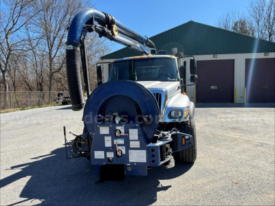 Truck-mounted vacuum system on a 2006 International 7500 with front-facing view showing the large blue vacuum hose reel and control panel at the rear.