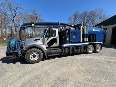International vacuum truck with large blue vacuum tank and hose reel mounted on chassis, front cab in gray, side view.
