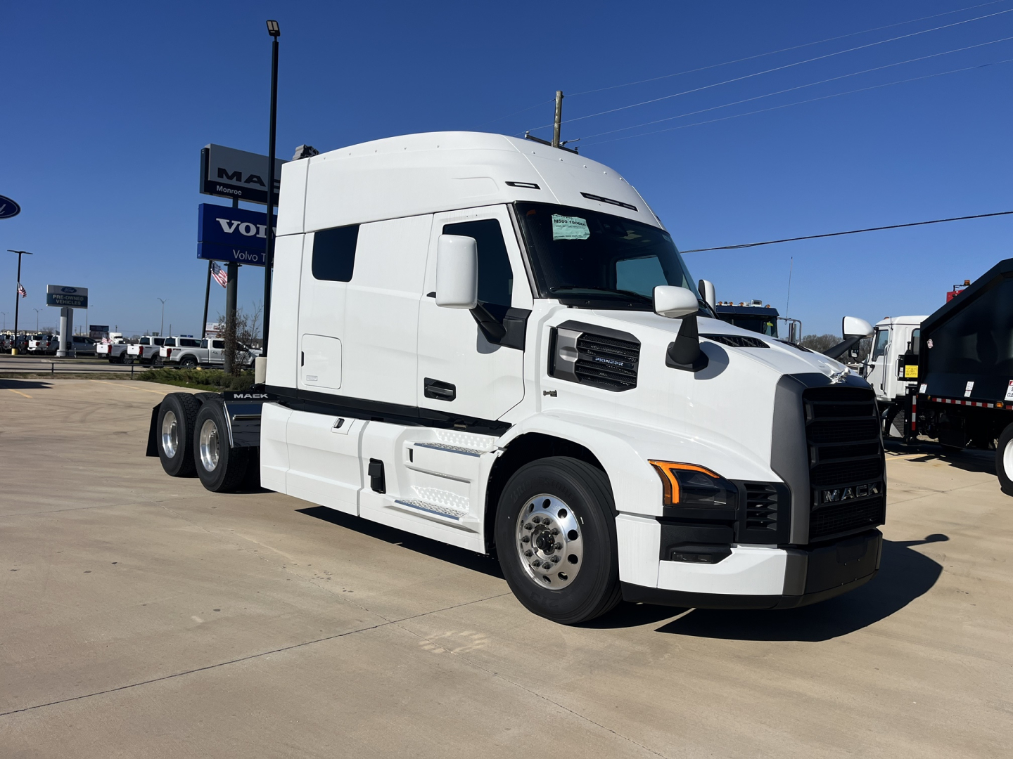 Mack PR64T76M cabover tractor with white exterior, side view showing sleeper cab, dual rear axles, and chrome grille.