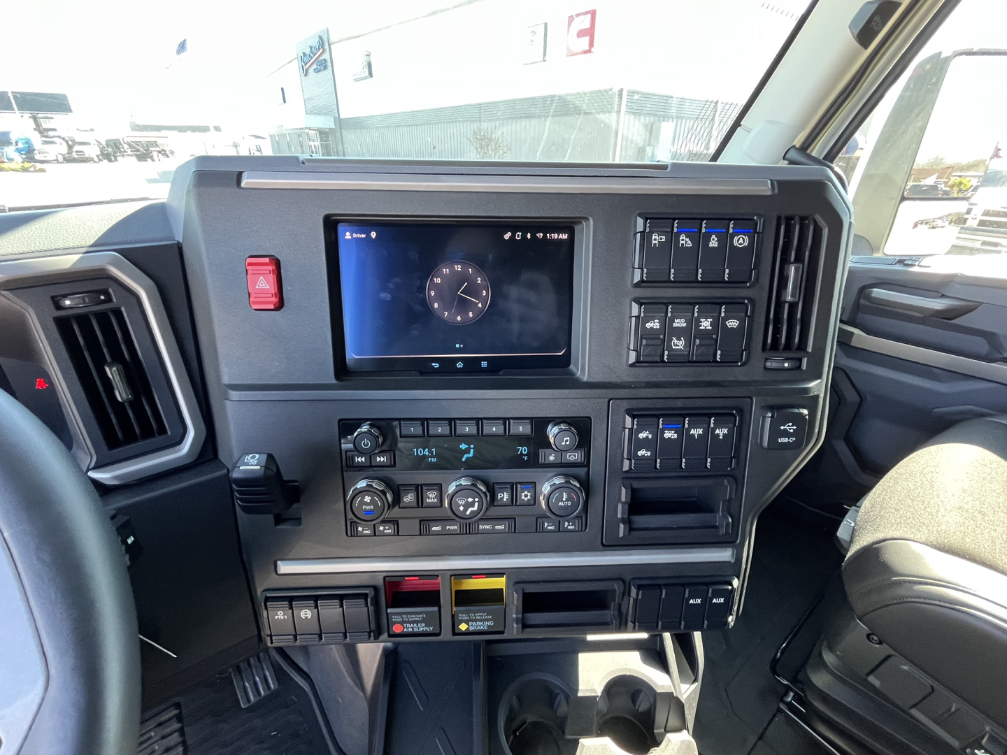 Dashboard of a 2026 Mack PR64T76M showing digital display, climate controls, switch panel, and cup holders.