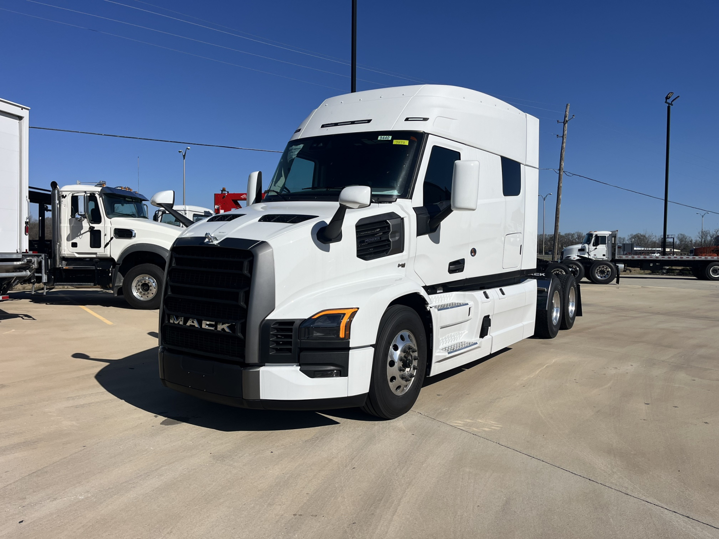 Mack PR64T76M conventional sleeper truck in white, front-left view showing grille, headlights, side mirrors, and dual rear axles.