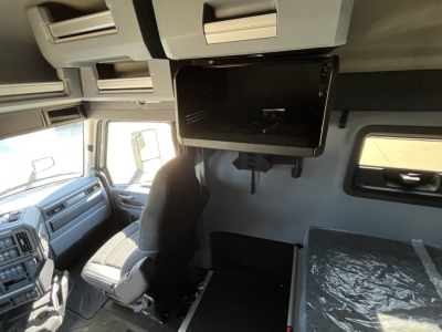 Mack PR64T76M tractor cab interior showing overhead bunk area and mounted monitor along with dashboard and driver seat.
