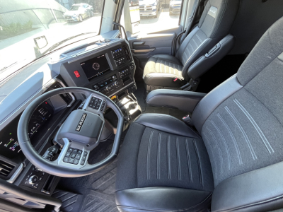 Mack PR64T76M truck cockpit interior showing steering wheel and driver seat with digital dashboard and center console.