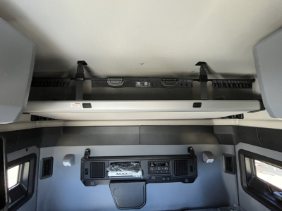 Cab interior of a Mack PR64T76M truck showing dashboard, overhead bunk, and control panel with 'MAC' emblem on center dash.