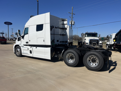 Front three-quarter view of a white Mack PR64T76M tractor with sleeper cab and dual rear axles, showing chassis and wheels.