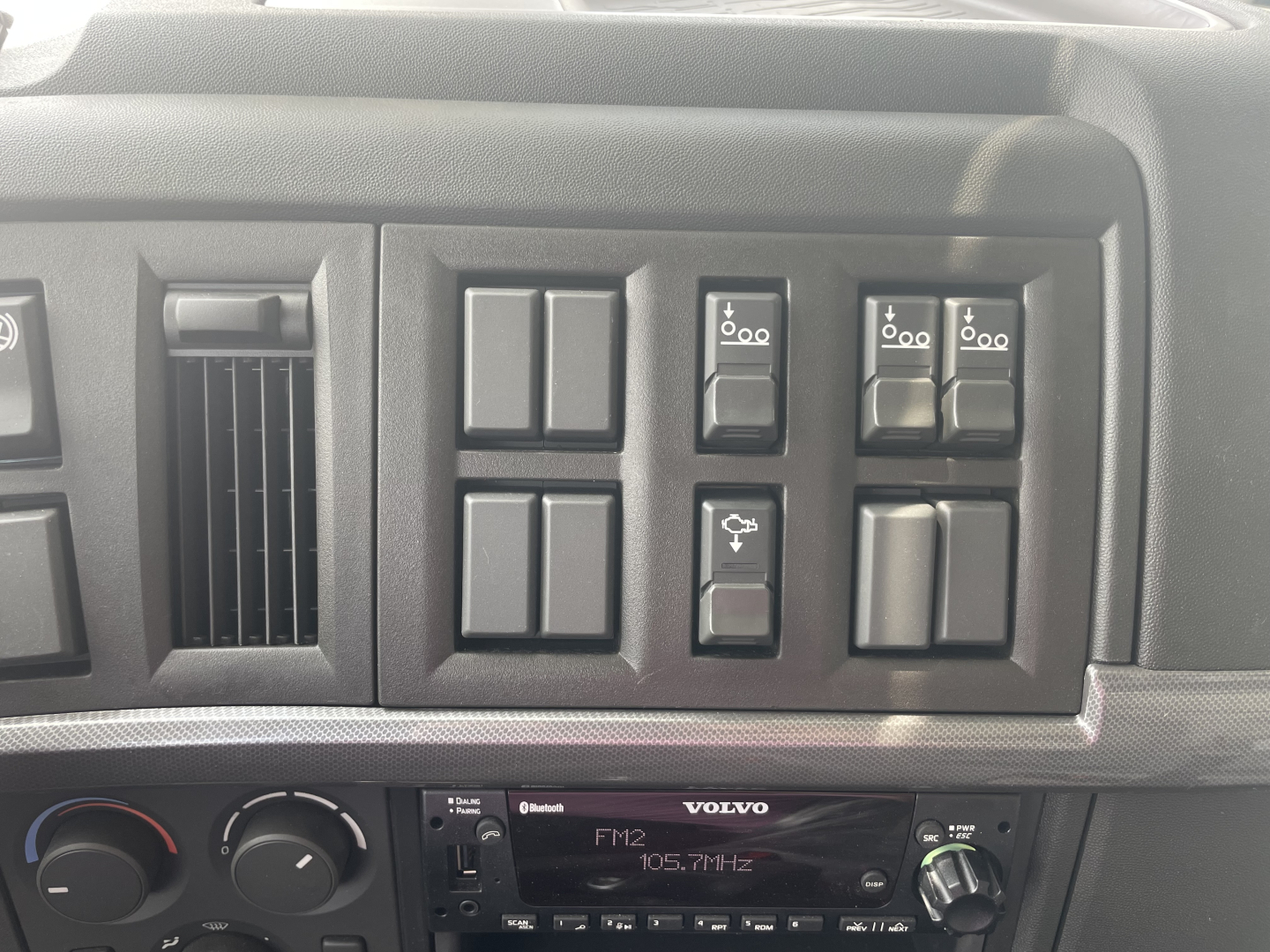 Volvo VHD64F300 truck dashboard showing multiple switches and a Volvo FM2 radio unit.