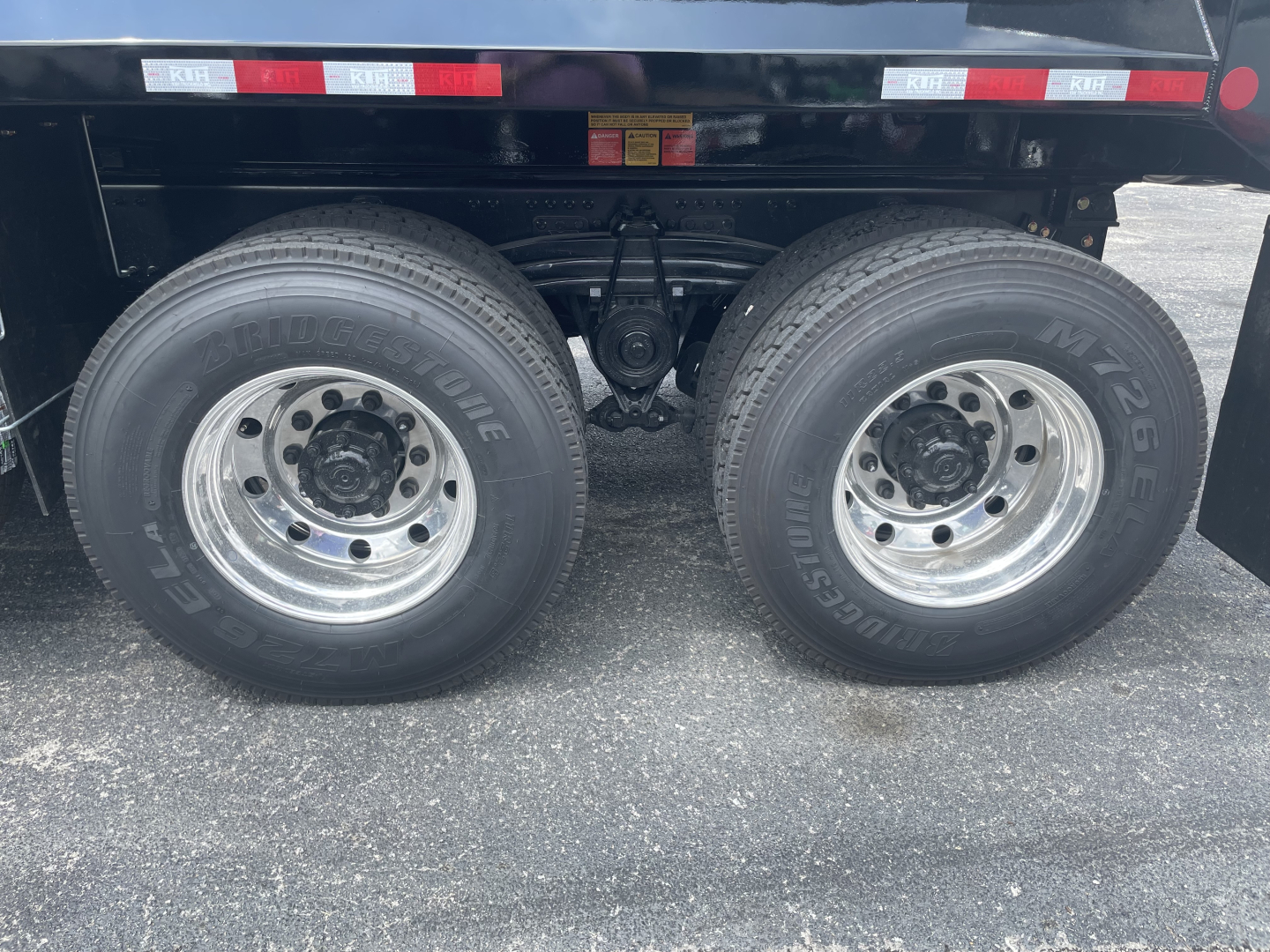 Dual rear wheels on a Volvo VHD64F300 dump truck showing tires, suspension, and undercarriage with chrome rims.